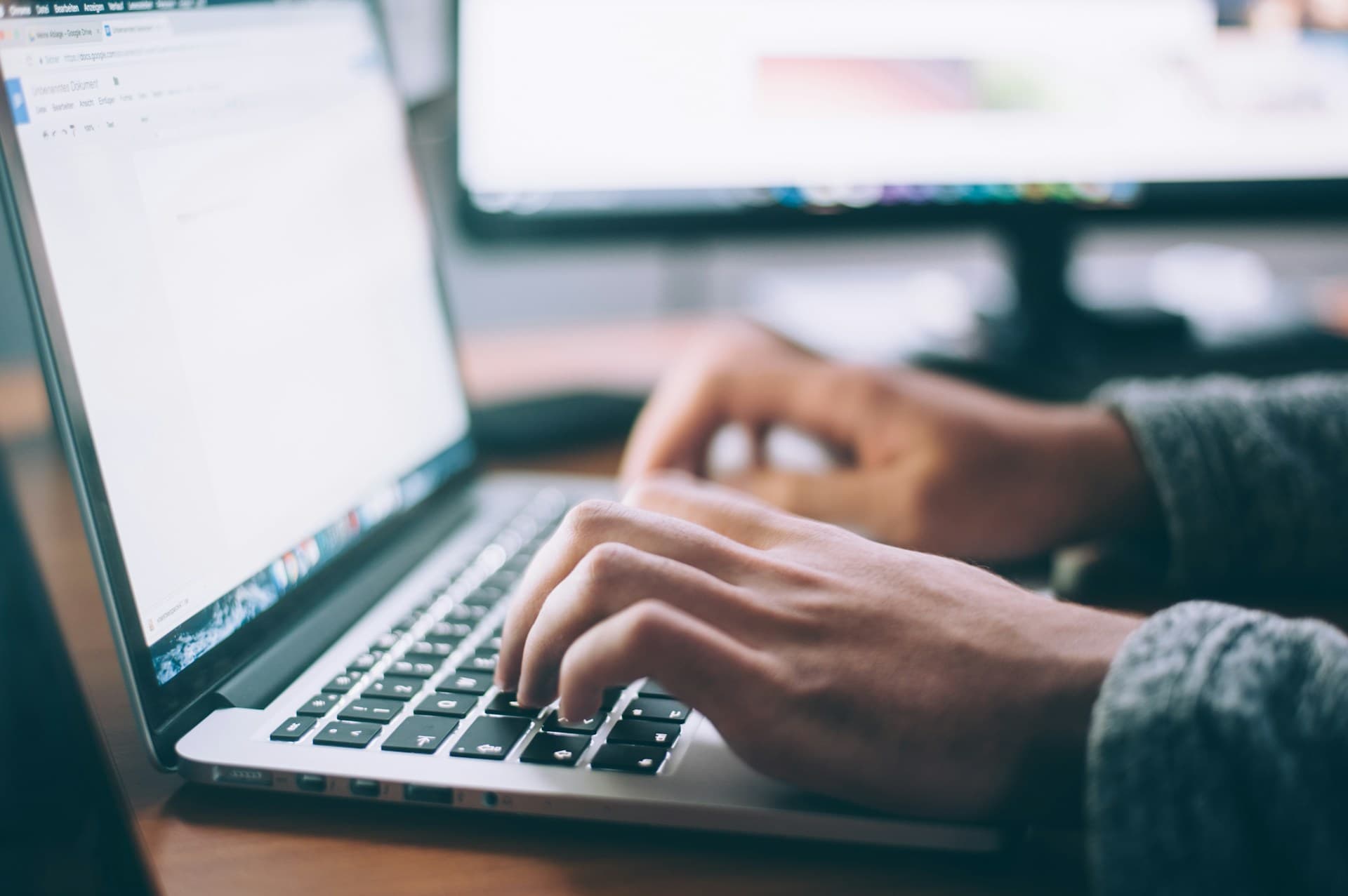 Person writing and working at a laptop in a bright workspace