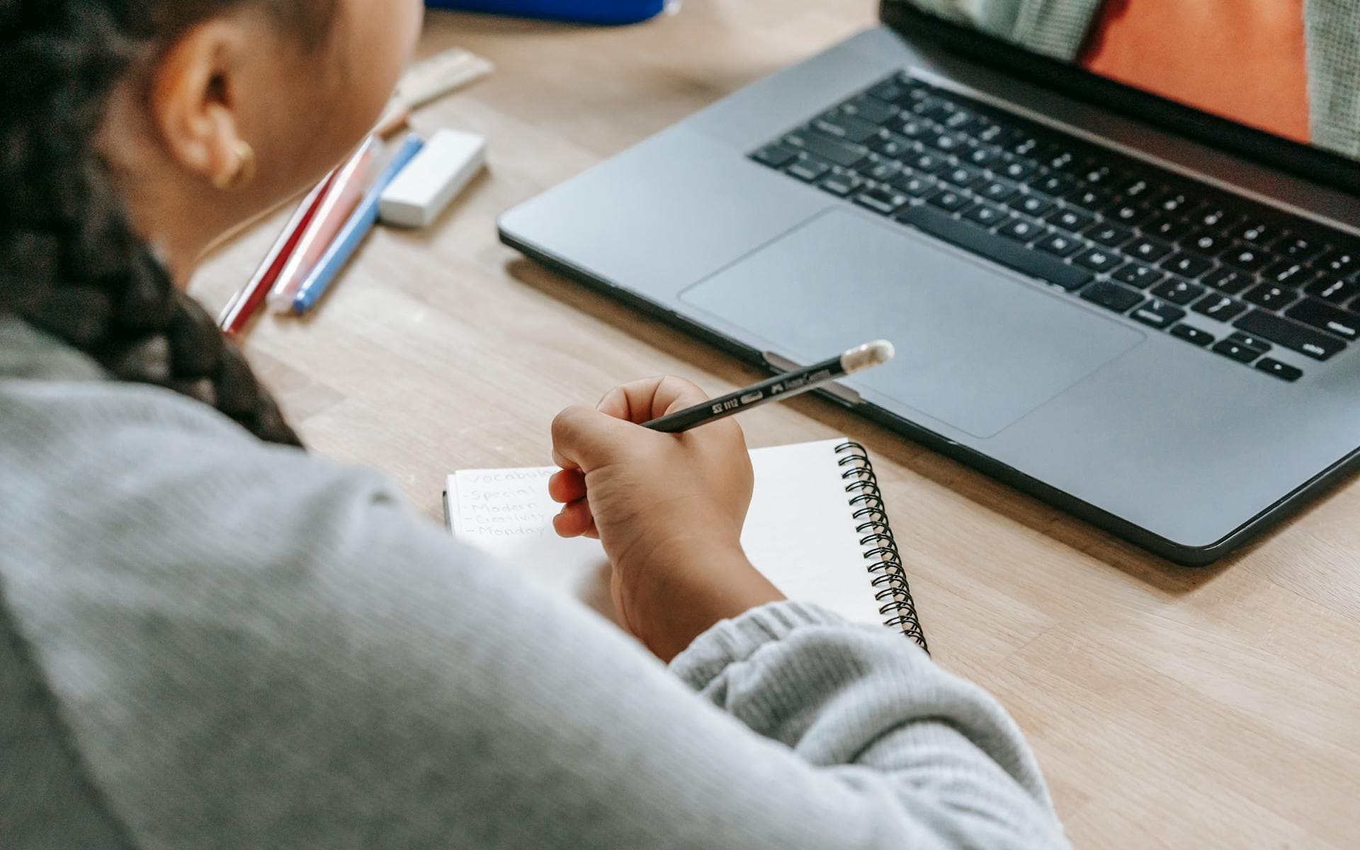 Student learning online with laptop and notes at a desk